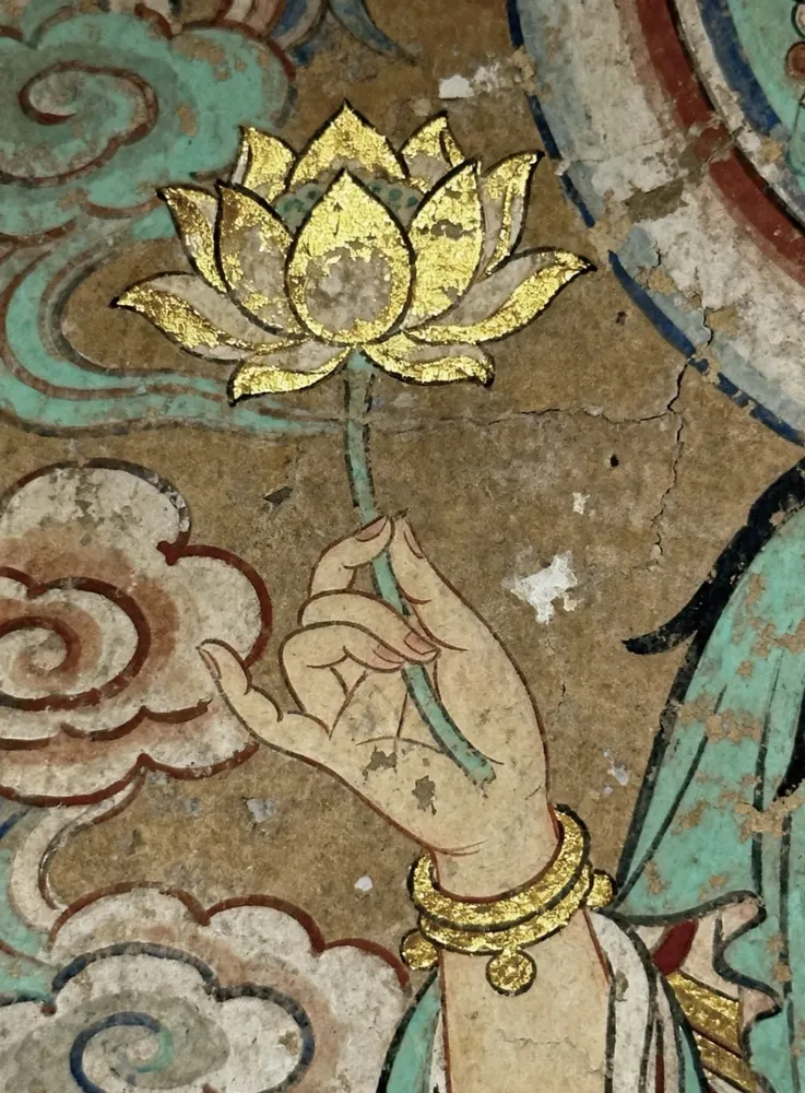 Dunhuang cave mural detail, Bodhisattva hand holding a gilded lotus blossom, ancient mineral pigment painting