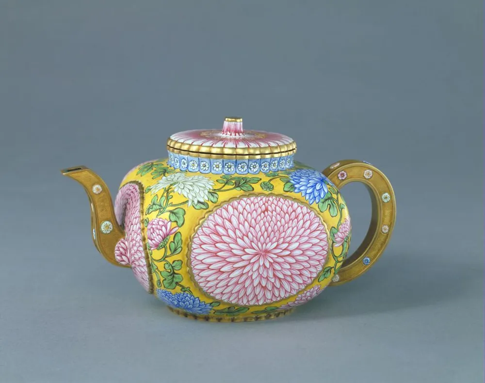 A Qing Dynasty Qianlong period painted enamel teapot with vibrant yellow background and detailed pink and blue chrysanthemum floral medallions.