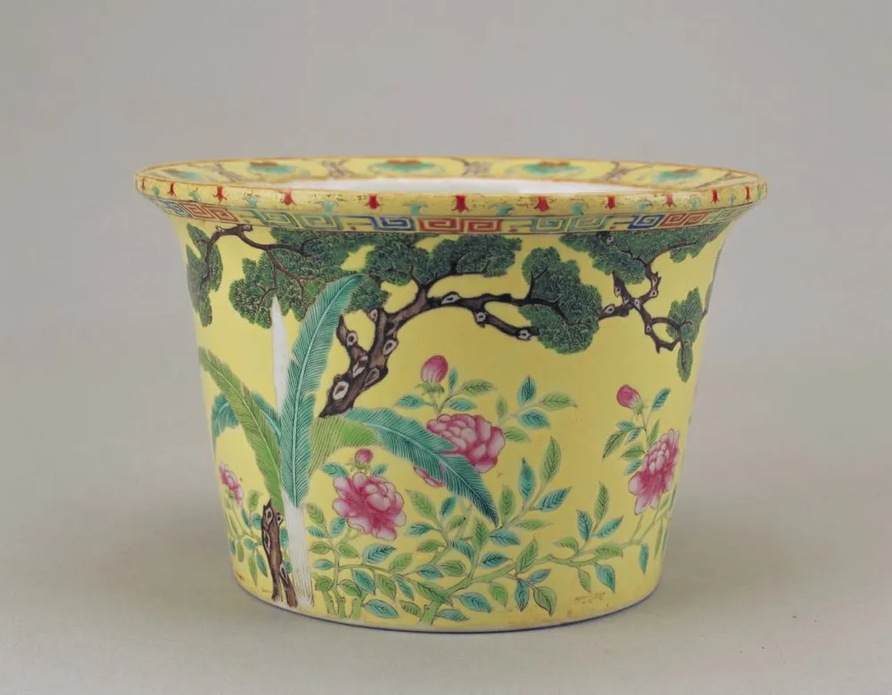 Qing‑dynasty yellow‑ground famille‑rose flower‑pot painted with hardy banana, pine tree and peony, Palace Museum collection.